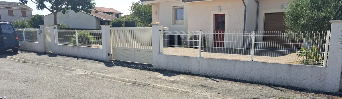 Clôture blanche posée sur un muret en bordure de rue