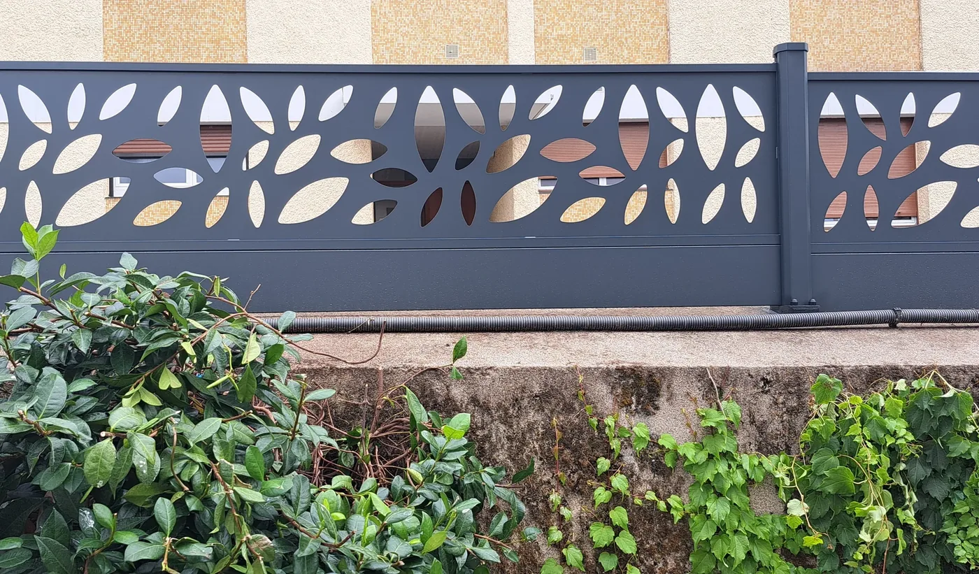 Clôture aluminium à panneaux décoratifs feuilles posée sur un muret
