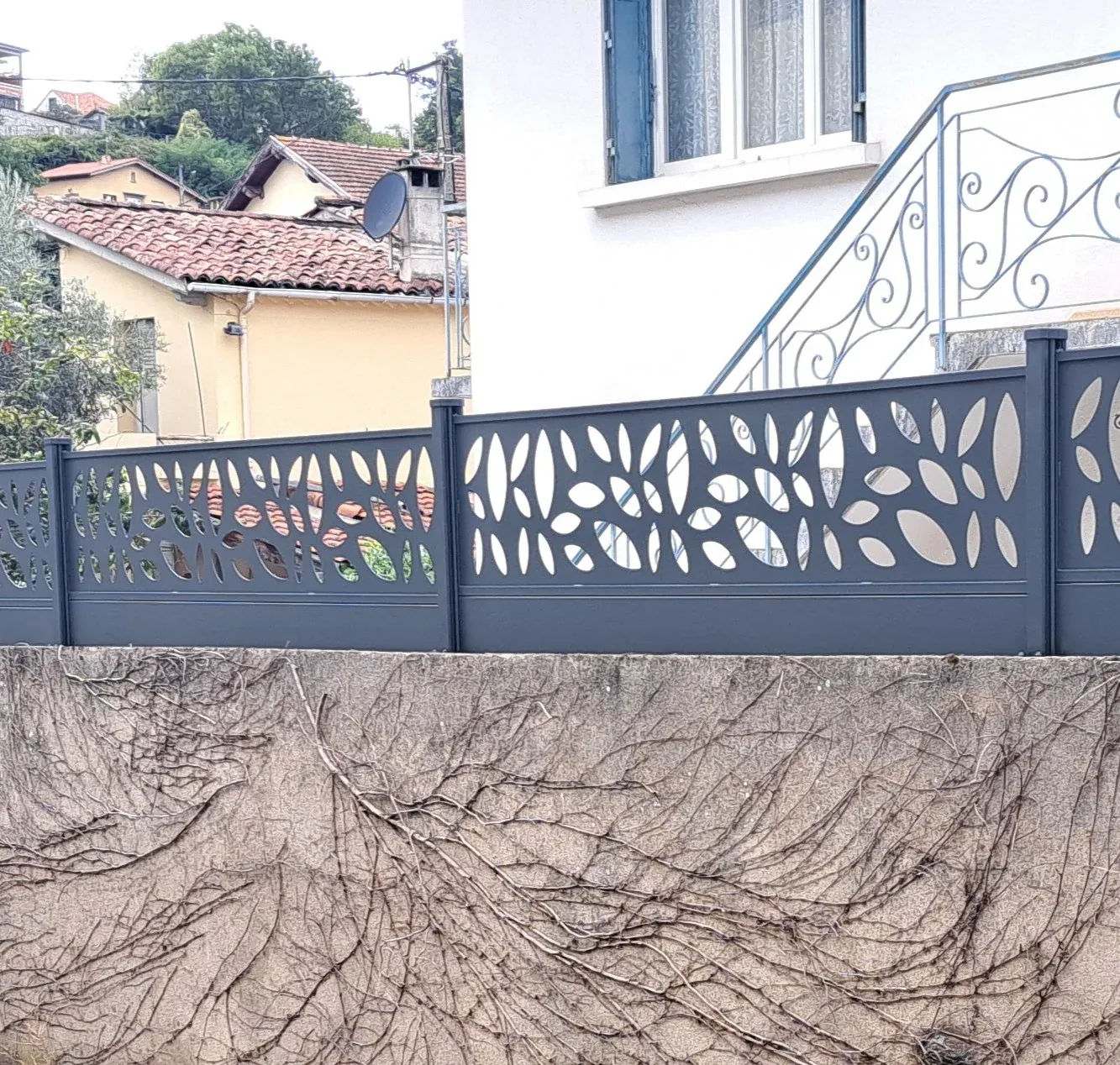 Clôture aluminium à panneaux décoratifs posée sur un muret de propriété