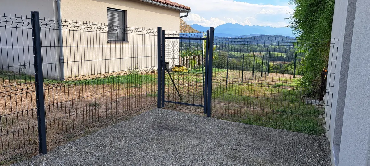 Portail barreaudé et clôture rigide installés à l'entrée d'une maison