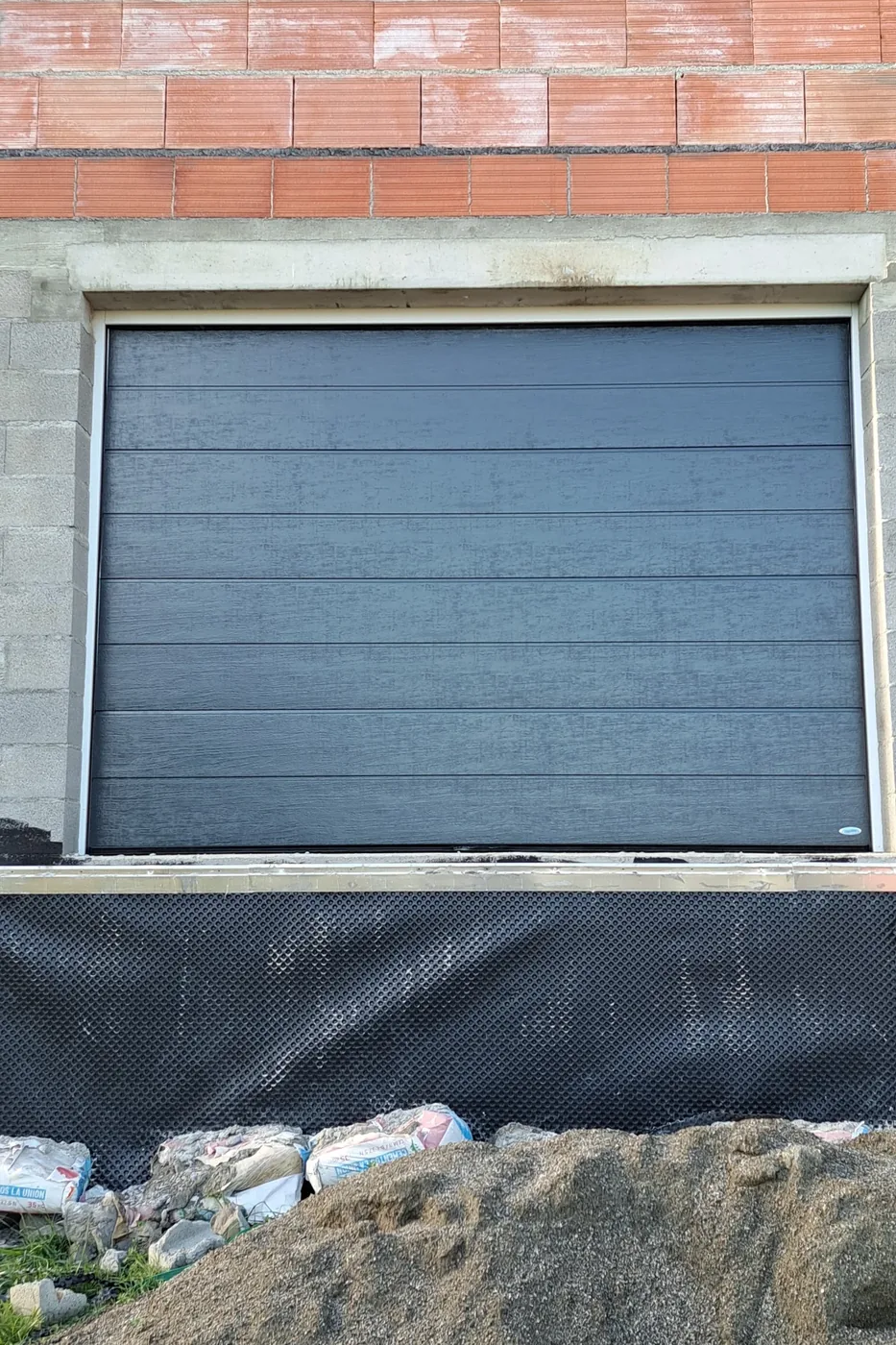 Porte de garage sectionnelle anthracite posée sur une maison en construction