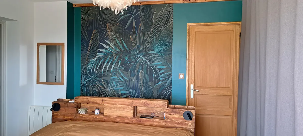 Chambre aménagée avec tête de lit en bois, appliques et miroir