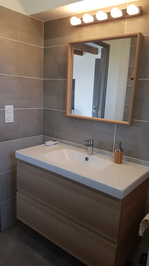 Salle de bains équipée d'un meuble vasque, d'un miroir et d'un éclairage