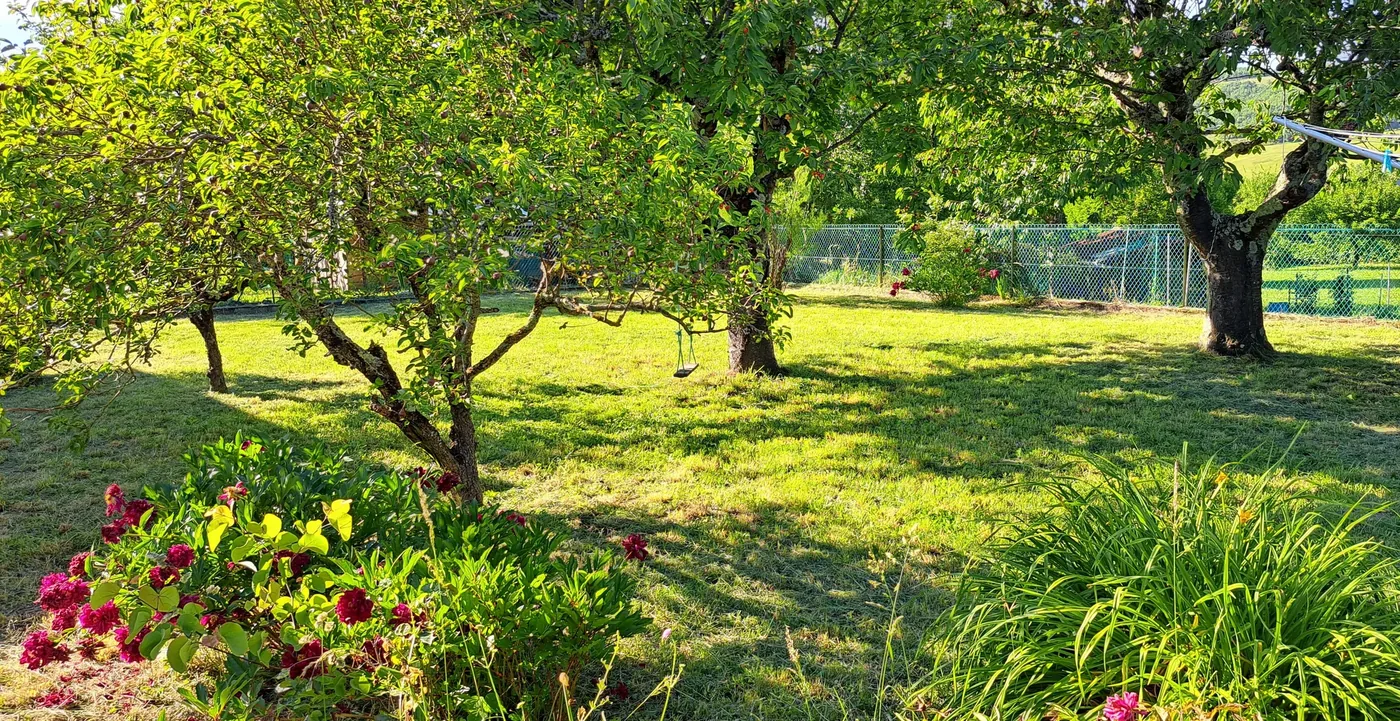 Jardin entretenu régulièrement : pelouse tondue, arbres taillés et massifs fleuris